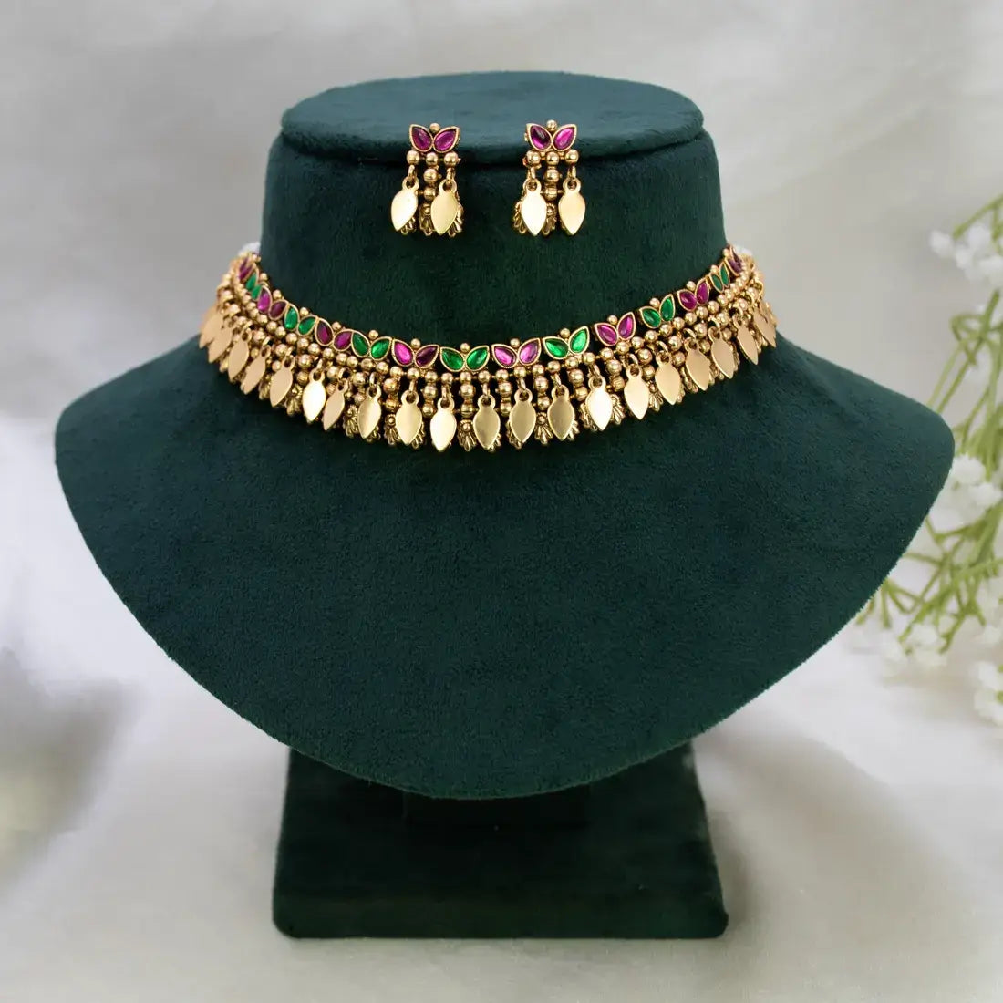 Antique Multi-colour Stone Elakkathali Choker Set displayed on a stand with matching earrings against a dark green backdrop.