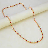 South Indian Coral Red and Golden Beaded Chain displayed on marble surface, featuring a pattern of red and gold beads.
