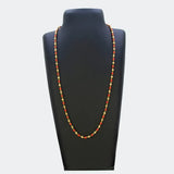 South Indian Coral Red and Golden Beaded Chain displayed on a black jewelry stand, showcasing its traditional design.