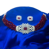Elegant Multi-Strand Crystal American Diamond Choker Set with maroon crystals and matching earrings on a blue satin background.
