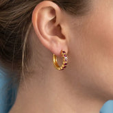 Gold Plated Stone Hoop Earrings for Women worn by a model showcasing ruby stones and gold finish.