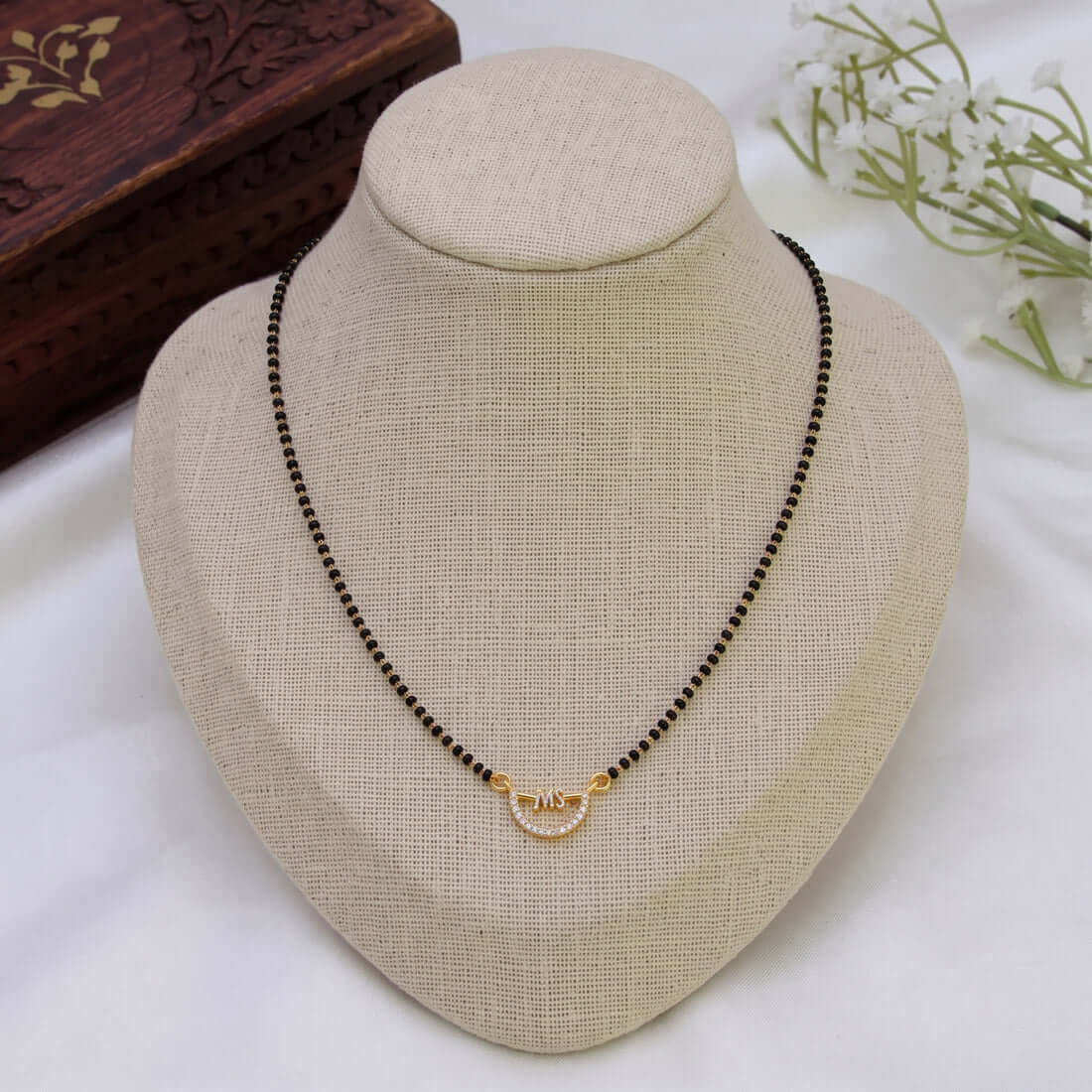Simple CZ Stone Pendant Mangalsutra Necklace displayed on a jewelry stand with a black bead chain and a gold accent.
