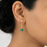 Gold Plated Green Crystal Hanging Drop Earrings worn by a model, featuring a gold button stud and green crystal bead.