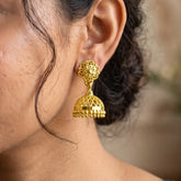 Net Design Gold Plated Filigree Jhumka Earrings showcased on a model's ear, highlighting exquisite temple jewelry craftsmanship.