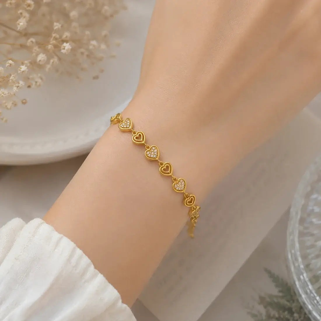 Gold Plated Stones and Outline Heart Bracelet worn on a wrist, featuring alternating heart links with sparkling stones.