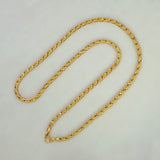 A gold-colored chain necklace with a textured, woven link design, displayed on a plain light gray background.