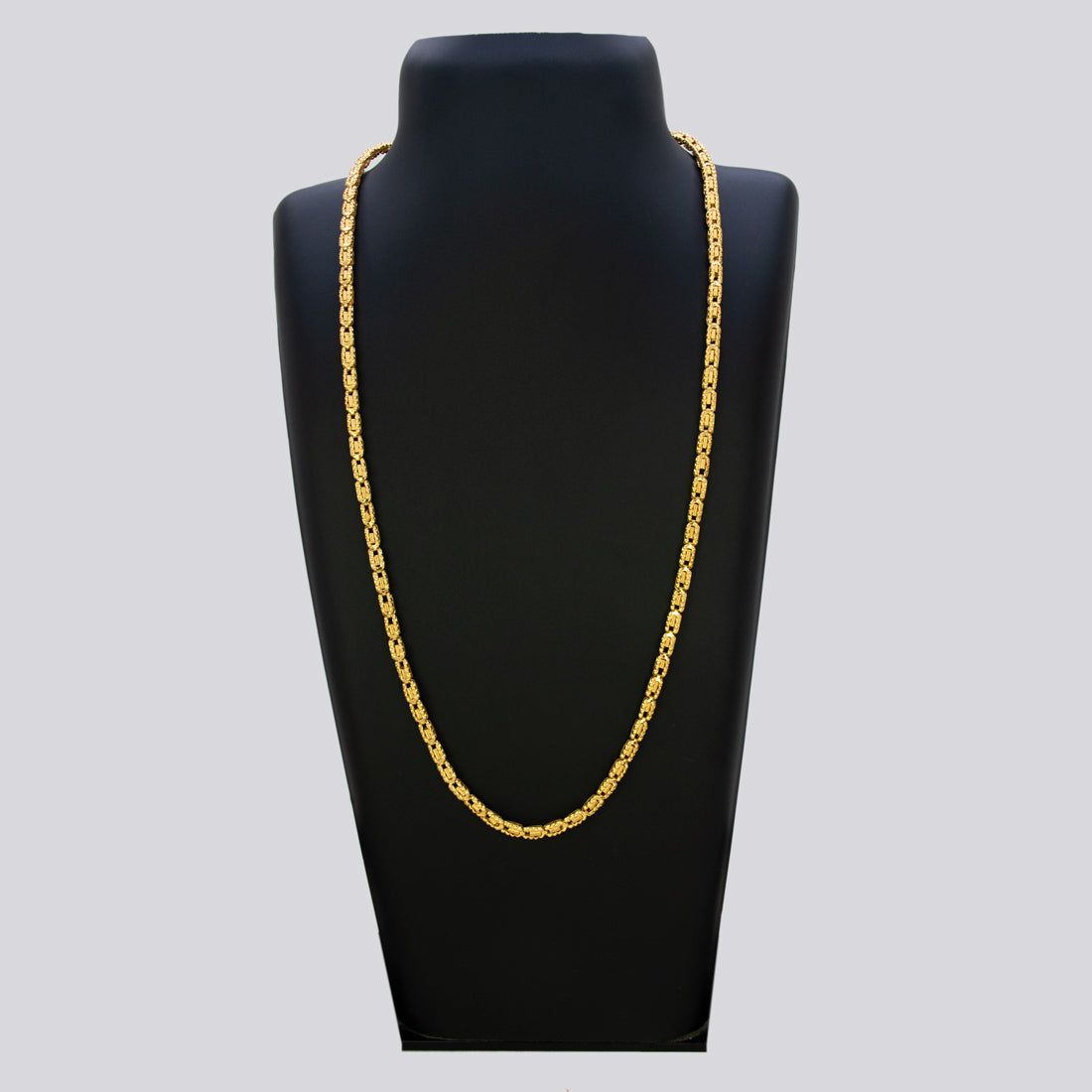 Gold chain necklace on a black mannequin bust against a gray background