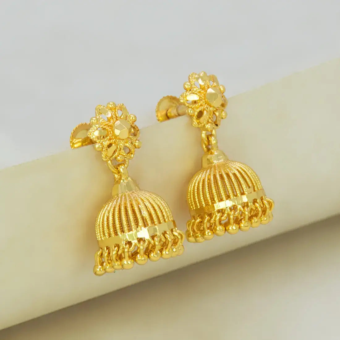 Gold earrings with intricate designs on a light background