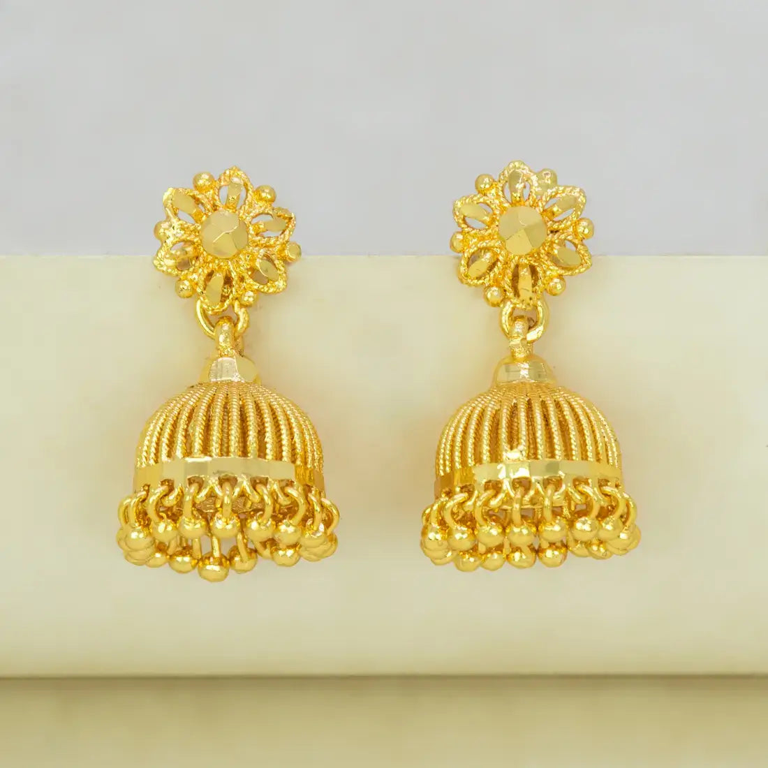 Gold earrings with intricate designs on a light gray background