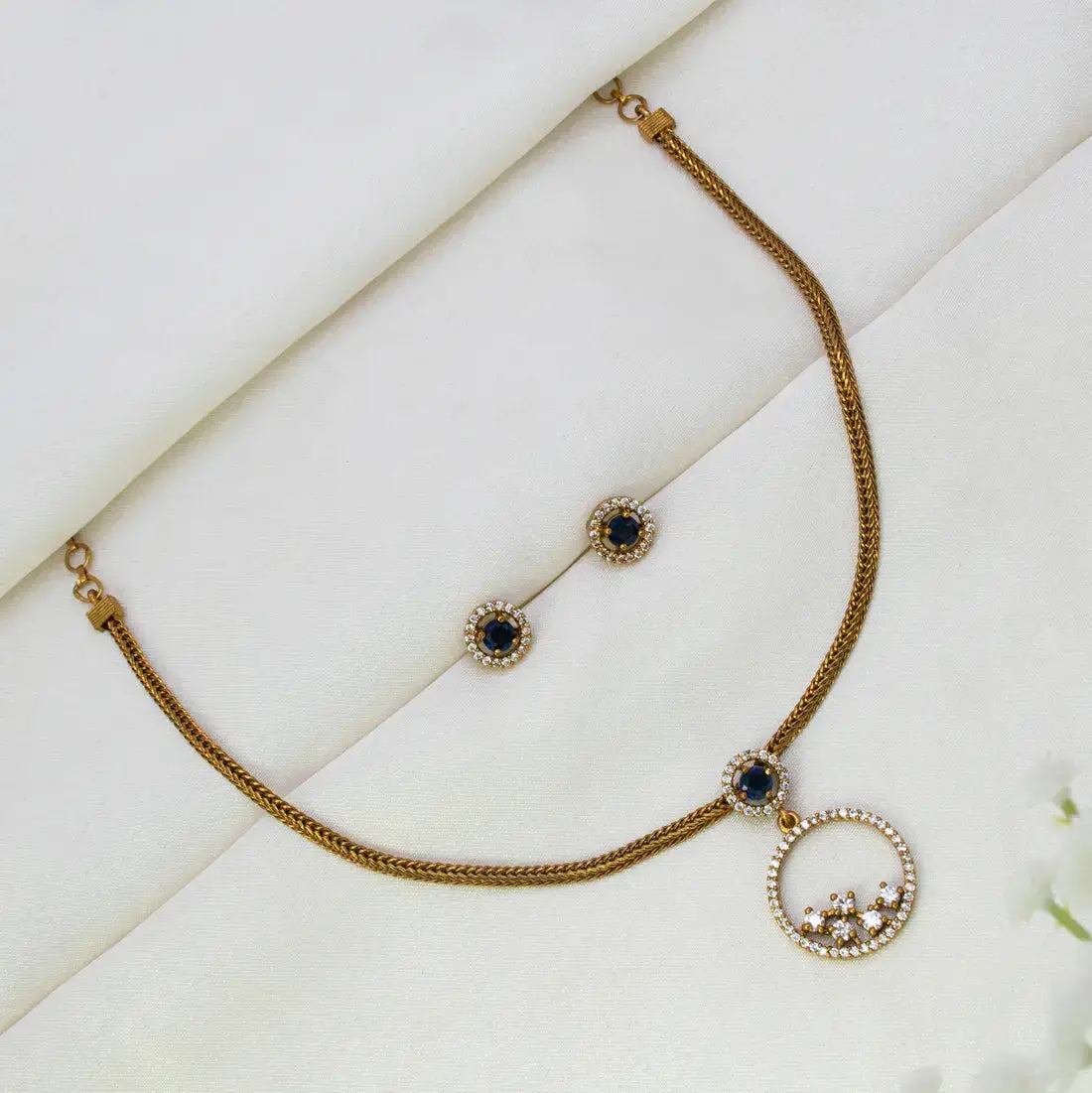 Victorian Gold-Plated Stone Necklace & Earring Set with dark blue oval stones and small cz accents, arranged on a soft white fabric background.