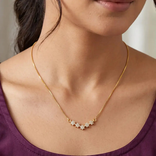 Gold Plated Five CZ Star Pendant Necklace worn by a woman, showcasing sparkling cubic zirconia stars on a delicate chain.