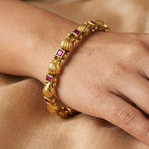 K Supreme antique gold bangle with raised paisley motifs and square kemp stones, perfect for festive occasions.