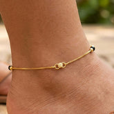 K Supreme gold plated brass anklet with box chain, black crystals, and gold beads. Minimalist design for women.