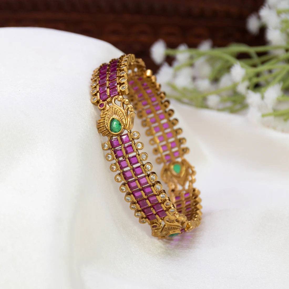 An Antique Peacock Kemp And CZ Stone Bangle displayed on a carved dark brown wooden surface.
