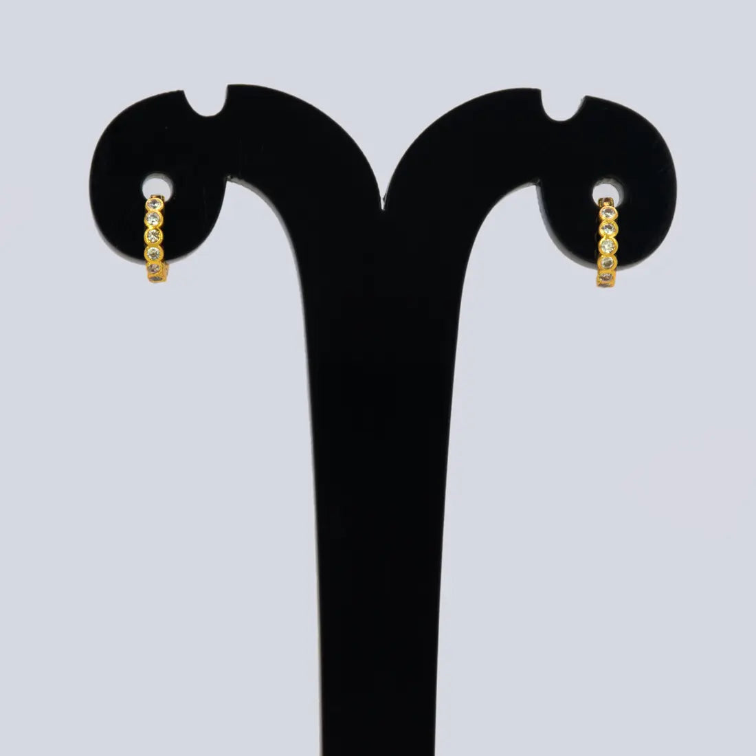 Gold Plated Stone Hoop Earrings for Women displayed on a stand, featuring shiny cubic zirconia stones.