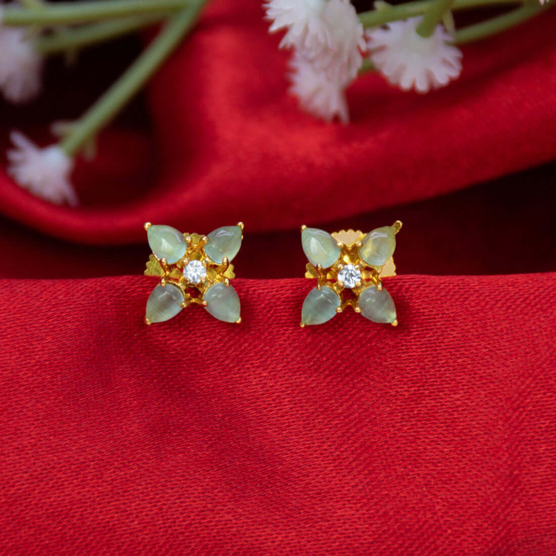 Gold-Plated Mint Green Flower CZ Ear Studs featuring mint green stones and sparkling white CZ center on red background.