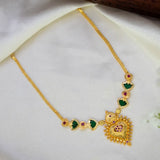 Gold-Plated Palakka Heart Pendant Necklace with a large ornate pendant, green Palakka stone, and small ruby stones, displayed on a soft white fabric background.