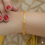 Delicate Gold Plated Wave Pattern Bangles worn on wrist, showcasing elegant wave design and lustrous finish.