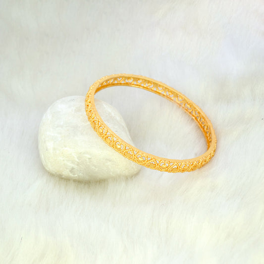 Elegant Gold Plated Heart Designer Medium Bangle resting on a smooth stone, showcasing its intricate design.