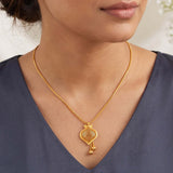 A close-up of a woman wearing a Gold-Plated Filigree Mesh Pendant Chain with a decorative pendant and small dangling beads, paired with a dark slate blue V-neck top.