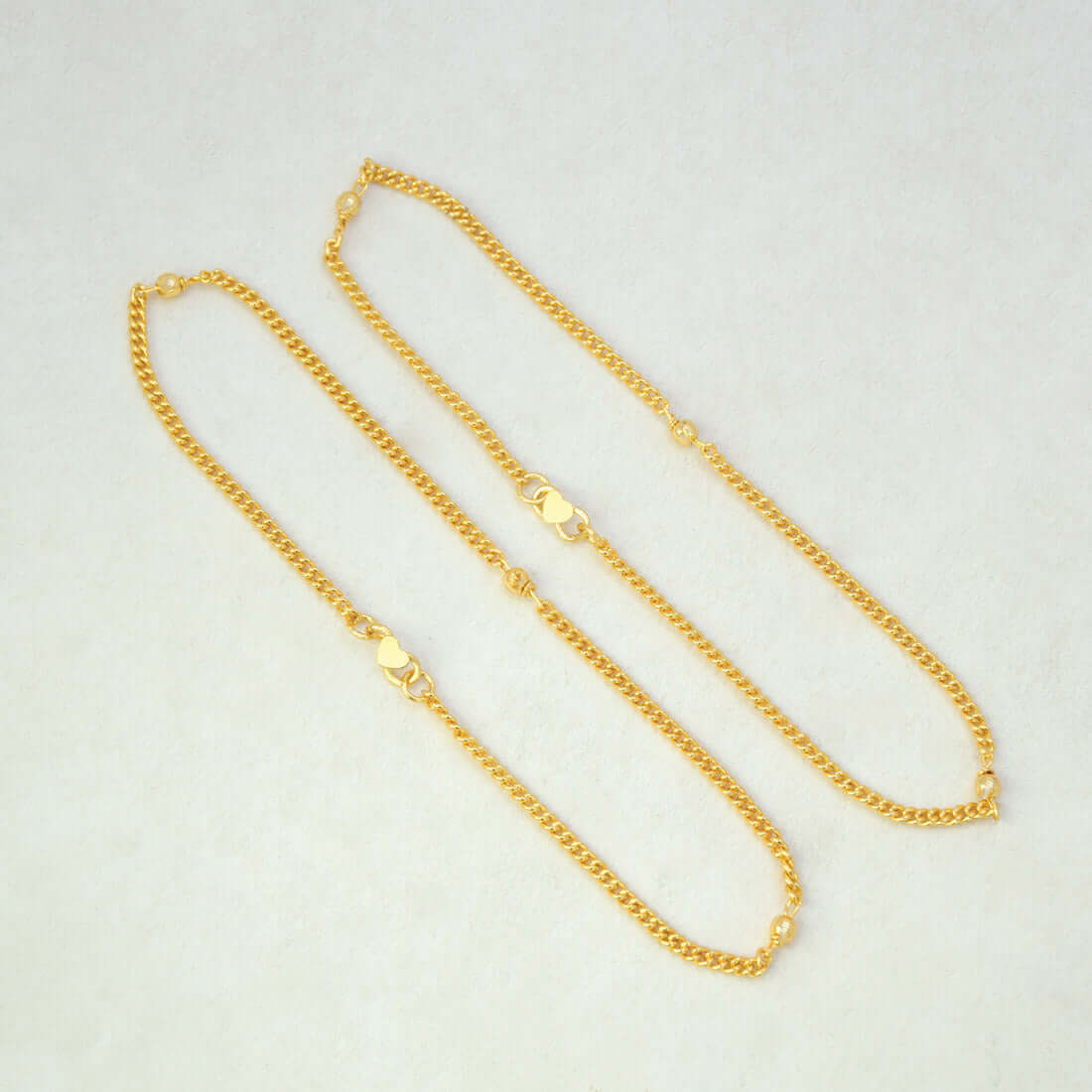 Trendy Gold-Plated Beaded Curb Link Chain Anklets on off white surface