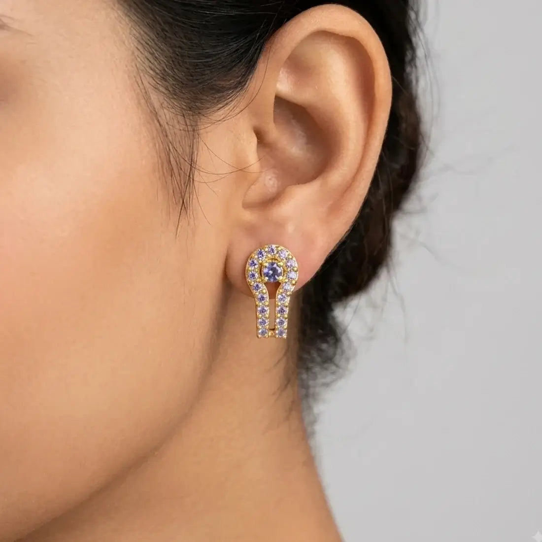 Gold Plated Purple CZ Stone Stud Earrings featuring CZ stones in a horseshoe design, showcased on an ear.