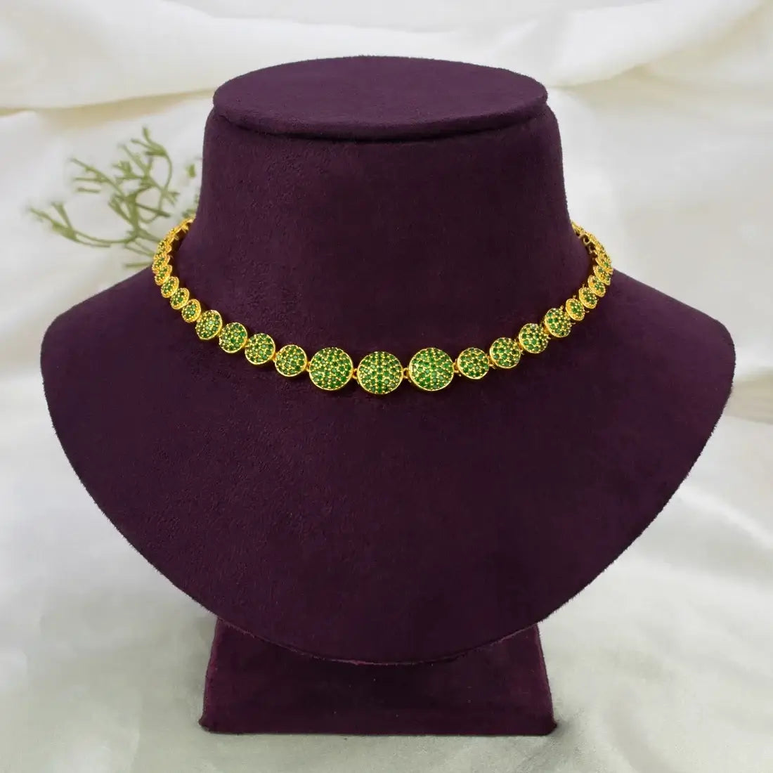 A Gold-Plated Round Design Stone Necklace displayed on a dark purple velvet jewelry bust against a soft white fabric background.