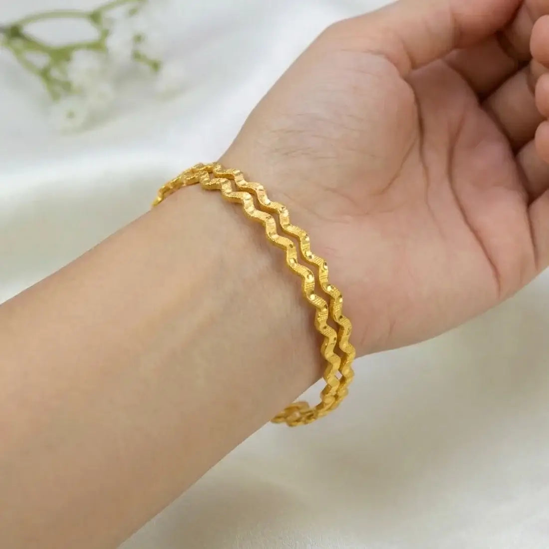 Gold Plated Zig Zag Design Bangles worn on a wrist showcasing the distinctive zigzag design and bright gold finish.