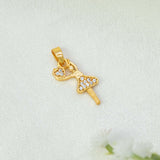 A gold-plated ballerina dancer pendant adorned with clear rhinestones, resting on a textured white fabric background with small white flowers in the corner.