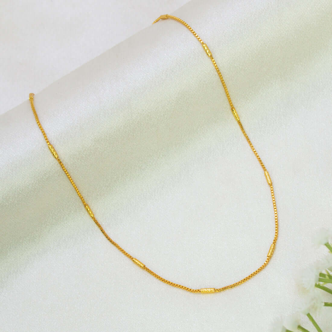 A delicate Gold-Plated Barrel Box Baby Chain with small cylindrical links, displayed on a soft, light-colored fabric background.
