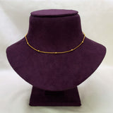 A Gold-Plated Beaded Curb Link Baby Chain necklace with small bead-like links, displayed on a dark purple velvet jewelry bust against a light off-white background.