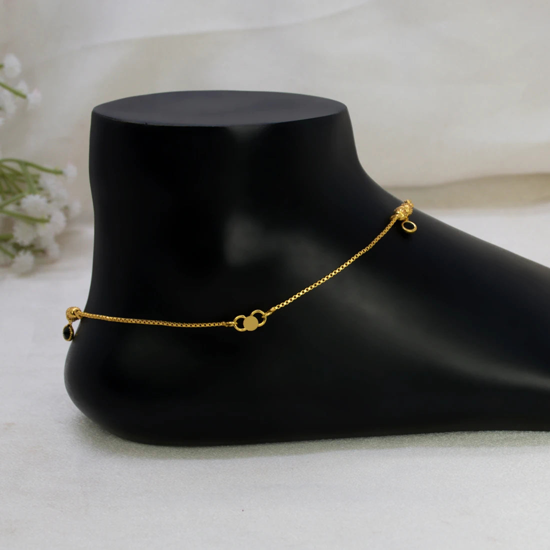 Gold-Plated Black Crystal Gold Bead Anklets with a small heart-shaped charm and a tiny dangling bead, displayed on a black mannequin foot against a soft white fabric background.