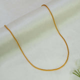A Gold-Plated Foxtail Chain for Babies necklace draped in a U-shape over a soft, light cream-colored fabric background.