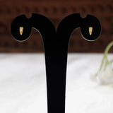 A pair of Gold-Plated Single CZ Stone Second Stud Earrings displayed on a black dual-ear jewelry stand against a softly blurred indoor background.