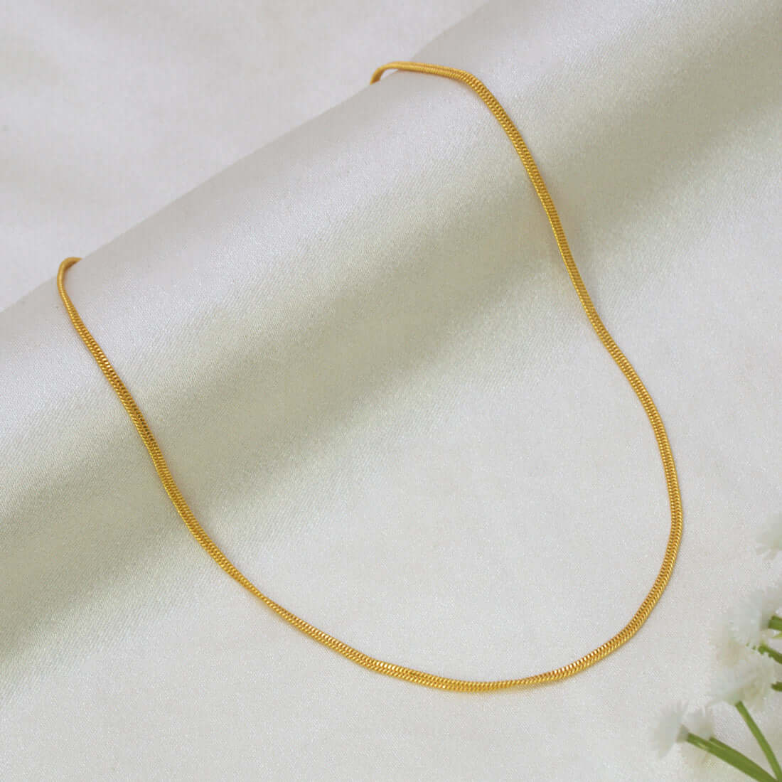 A Gold-Plated Sonali Chain for Babies & Kids draped in a U-shape on a soft, off-white textured fabric background.