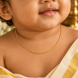 A close-up of a baby wearing a delicate Gold-Plated Thin Baby Gopi Chain - 15 Inch, styled with a cream and gold sari.