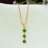 A gold chain necklace with a Gold-Plated Three-Tier Stone Floral Drop Pendant, featuring three small, green, flower-like charms set with tiny clear stones, displayed on a white jewellery bust.
