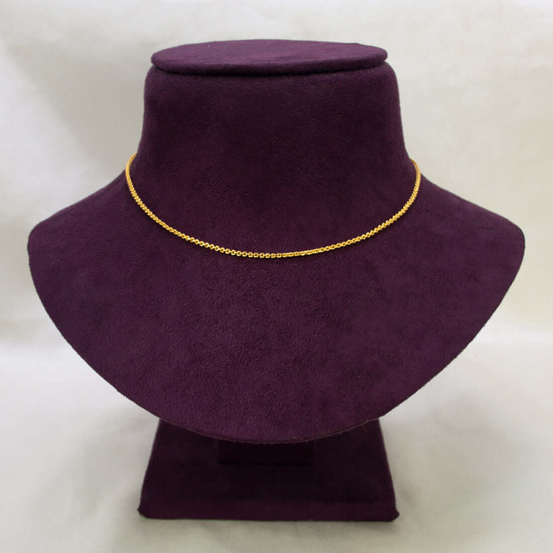 A Gold Plated Cutting Design Baby Chain necklace displayed on a purple velvet jewelry bust against a light off-white background.