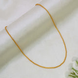A delicate Gold Plated Savitham Chain for Kids necklace draped in a U-shape over a soft, off-white satin fabric background with small white flowers in the corner.