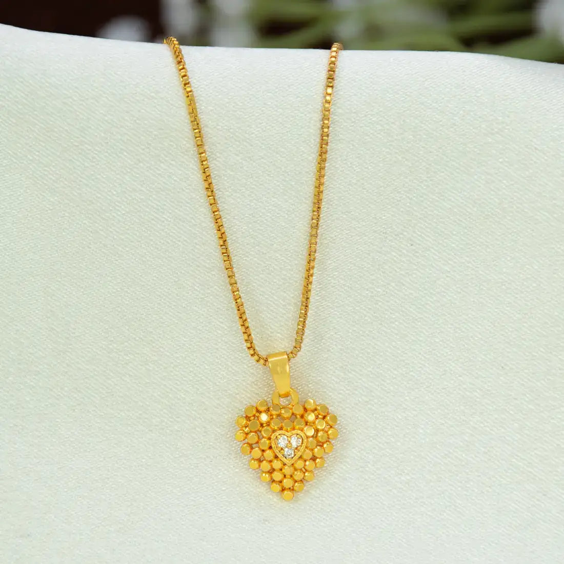 A gold heart pendant necklace with a Heart-Shaped Gold-Plated CZ pendant and a small clear heart in the center, displayed on a white jewelry bust.