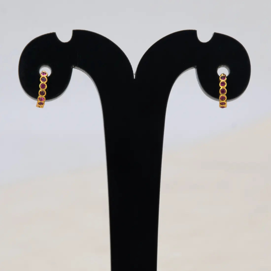 Gold Plated Stone Hoop Earrings for Women showcasing elegant ruby stones on a display stand.