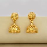 Pair of gold-plated jhumka earrings on a beige surface with a light gray background