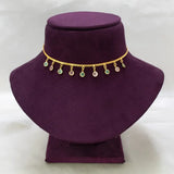 A gold chain necklace with small dangling round charms, including green and iridescent stones, displayed on a purple velvet jewelry bust against a white background.