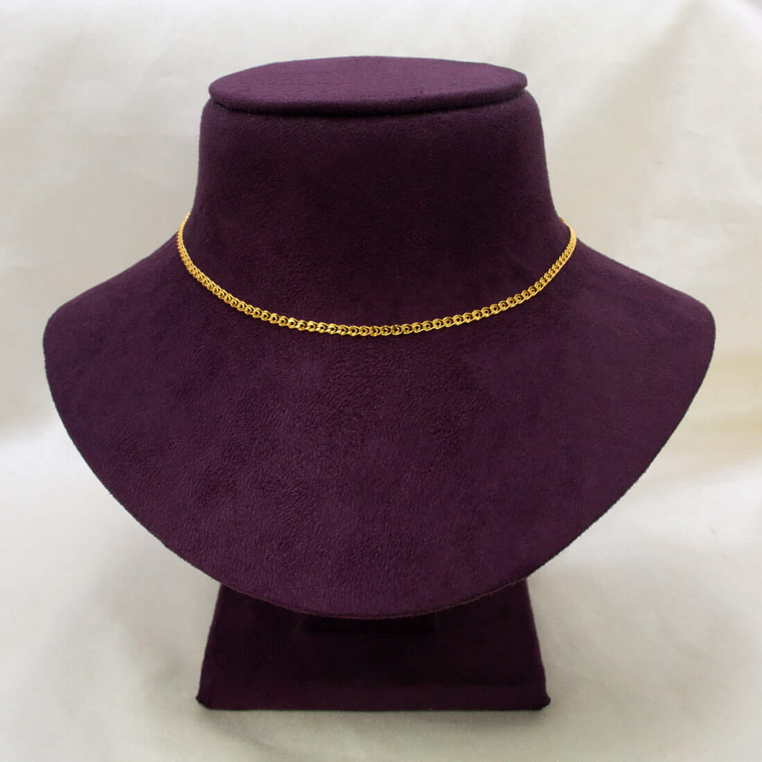 A delicate Unsex Gold-plated Double-link Chain necklace displayed on a dark purple velvet jewellery bust against a light off-white background.