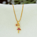 A gold-plated ballerina dancer pendant  necklace with a heart-shaped head and a tutu decorated with small pink stones, displayed on a white jewelry bust.