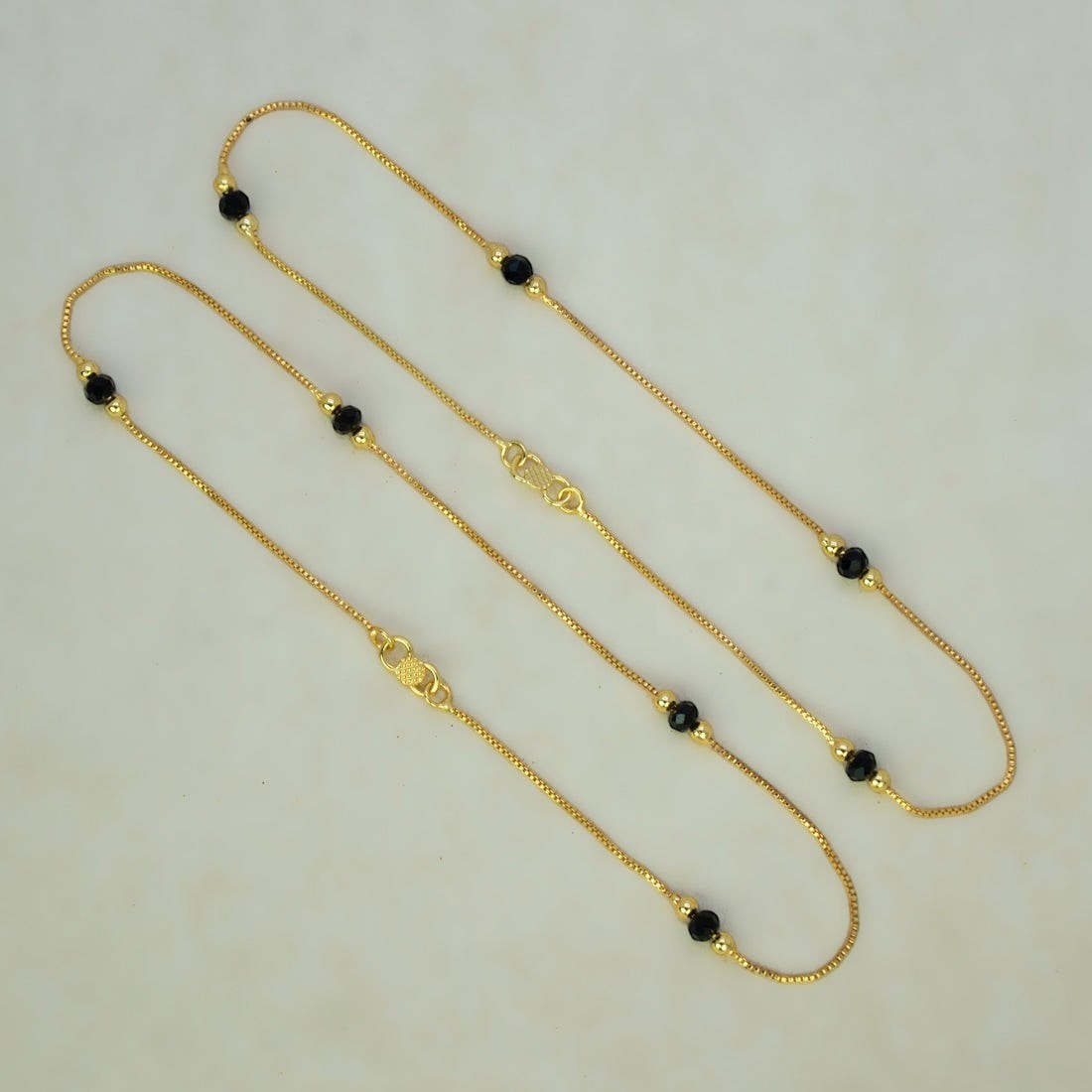 K Supreme gold plated brass anklets with box chain, black crystals, and gold beads. S hook closure.