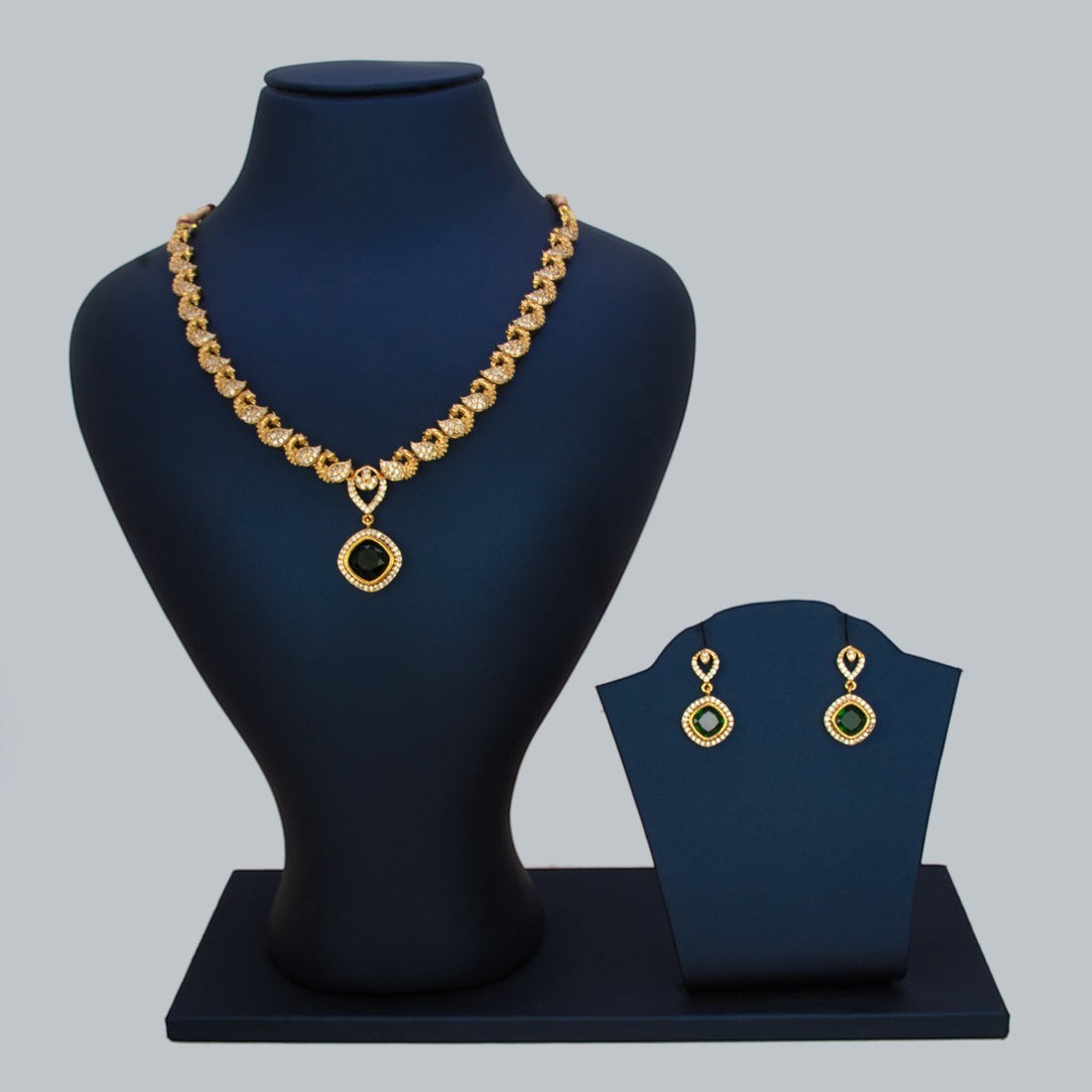K Supreme gold-plated necklace and earrings set with emerald green cubic zirconia stones and peacock motifs.