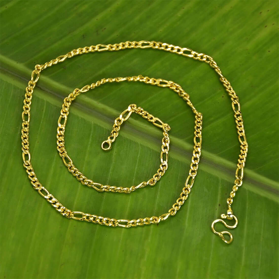 One Gram Gold Trendy Thin Figaro Unisex Sachin Chain showcased on a green leaf background.